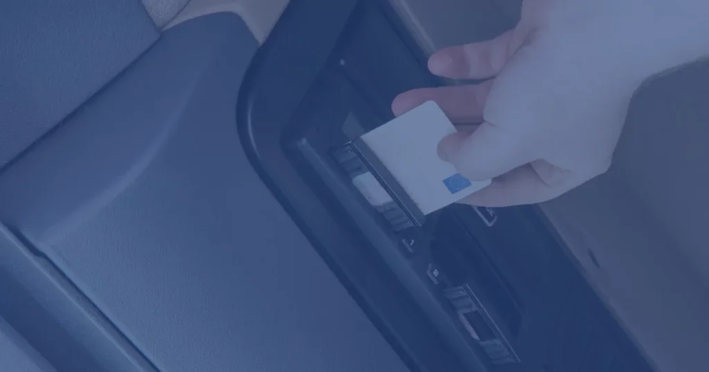 Zdjęcie przedstawiające tachograf oraz dłoń wkładająca do niego kartę kierowcy